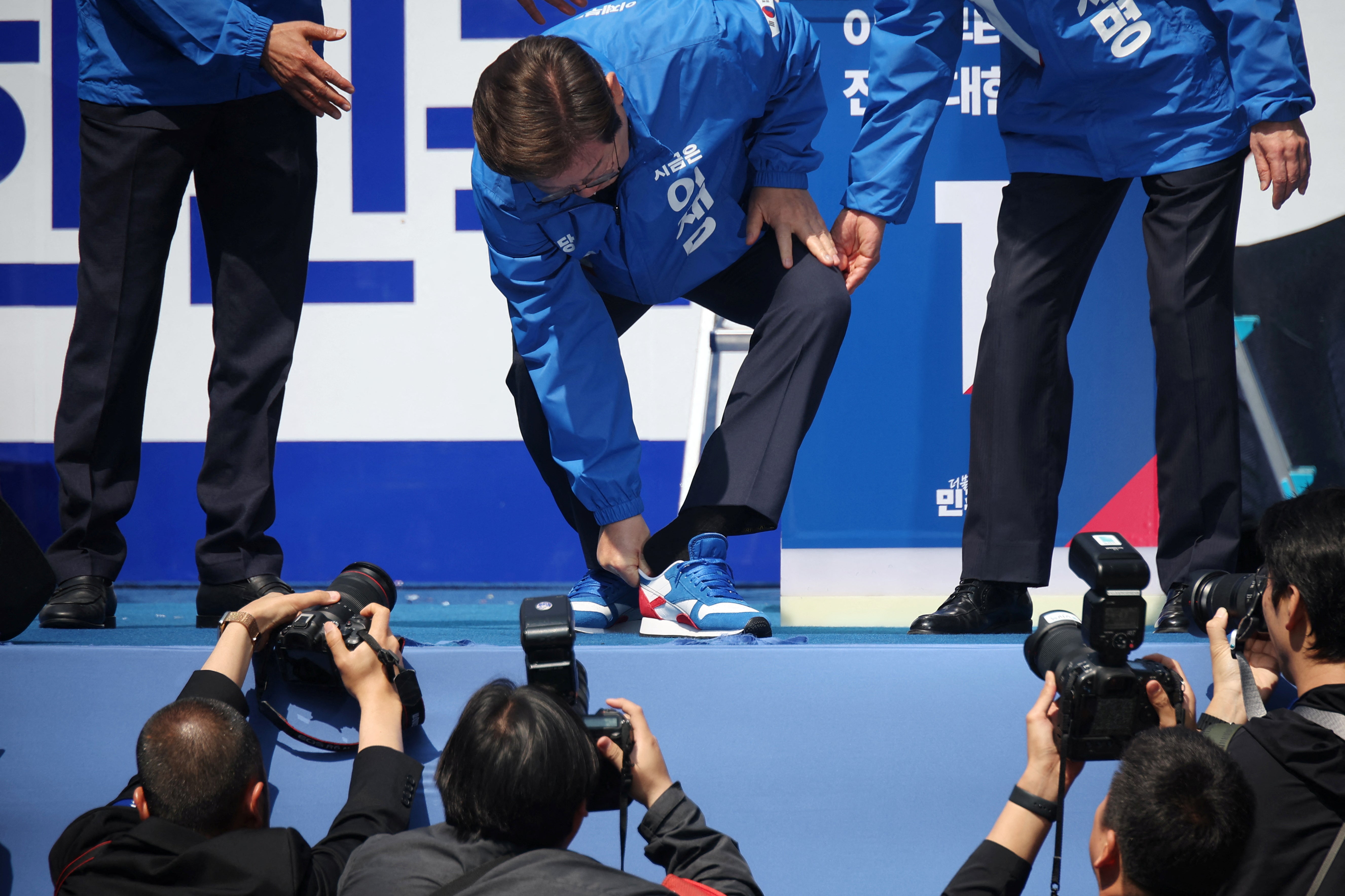 Lee Jae Myung changes his shoes during his election campaign rally in Seoul
