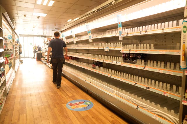 <p>A man walks past empty shelves in a branch of the Co-op in Manchester last week</p>