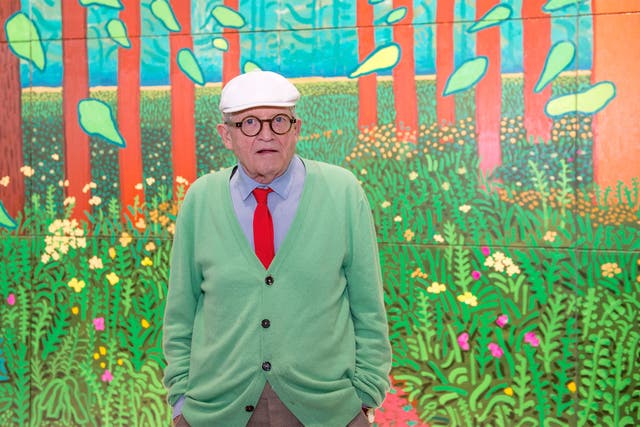 <p>David Hockney poses in front of his painting, ‘The Arrival of Spring in Woldgate, East Yorkshire in 2011’</p>