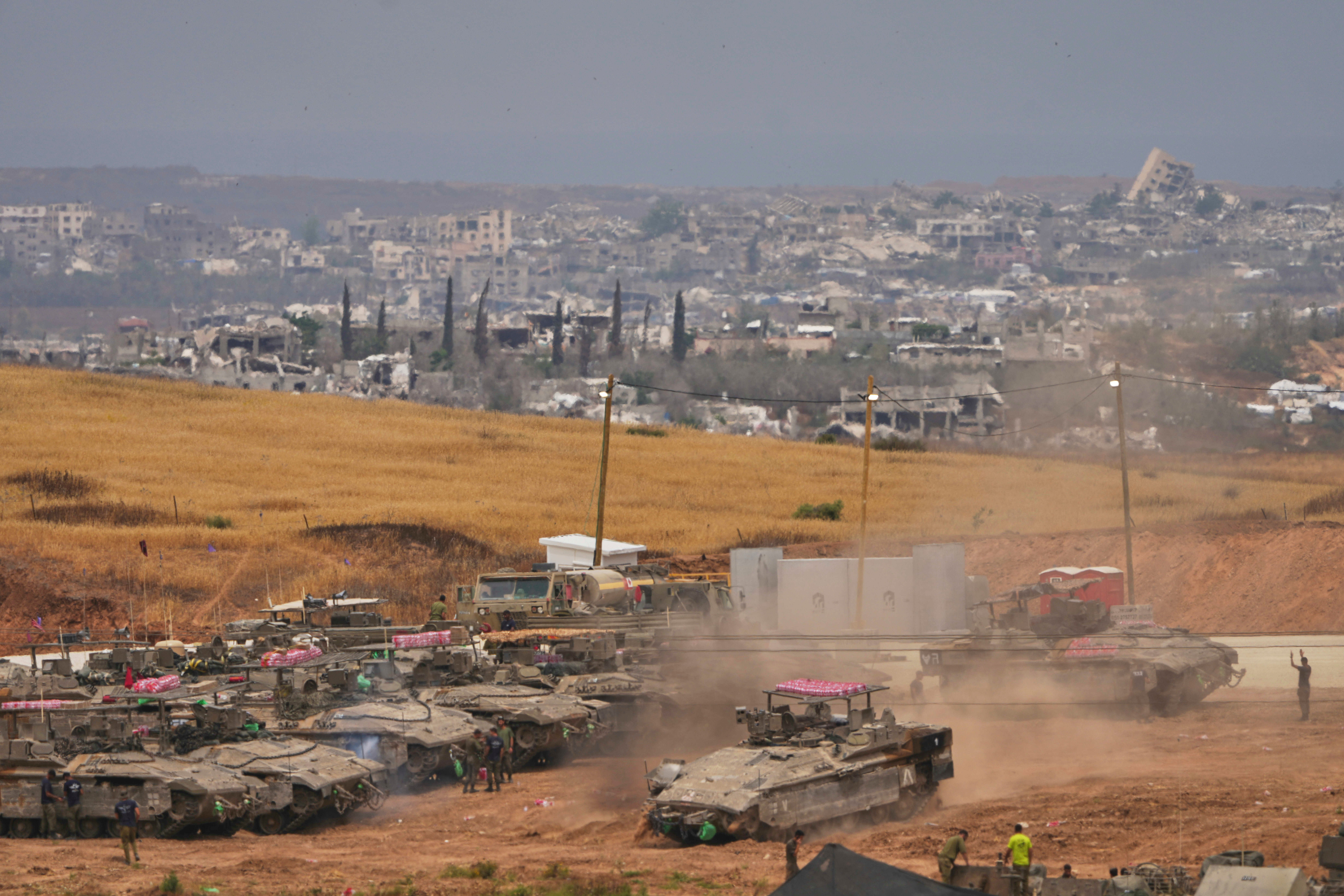 Israeli soldiers work on tanks and APCs at a staging area near the border with the Gaza Strip, in southern Israel