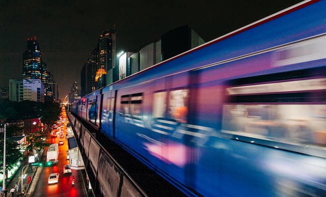 <p>A night train speeds above traffic in Bangkok, Thailand</p>