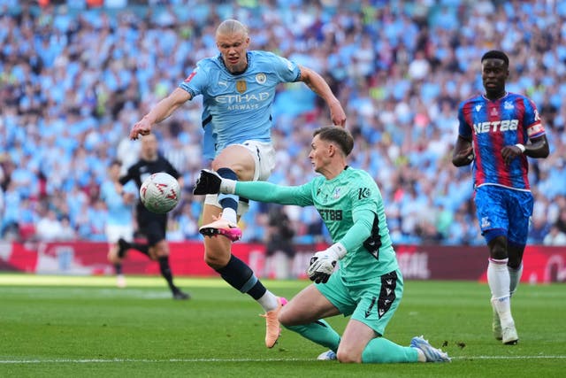 <p>Manchester City's Erling Haaland, left, challenges for the ball with Crystal Palace's goalkeeper Dean Henderson</p>