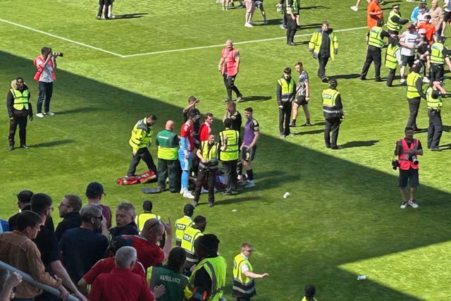 <p>Aberdeen’s Jack MacKenzie got treatment on the pitch as fans invaded the pitch after Dundee United’s victory over Aberdeen</p>