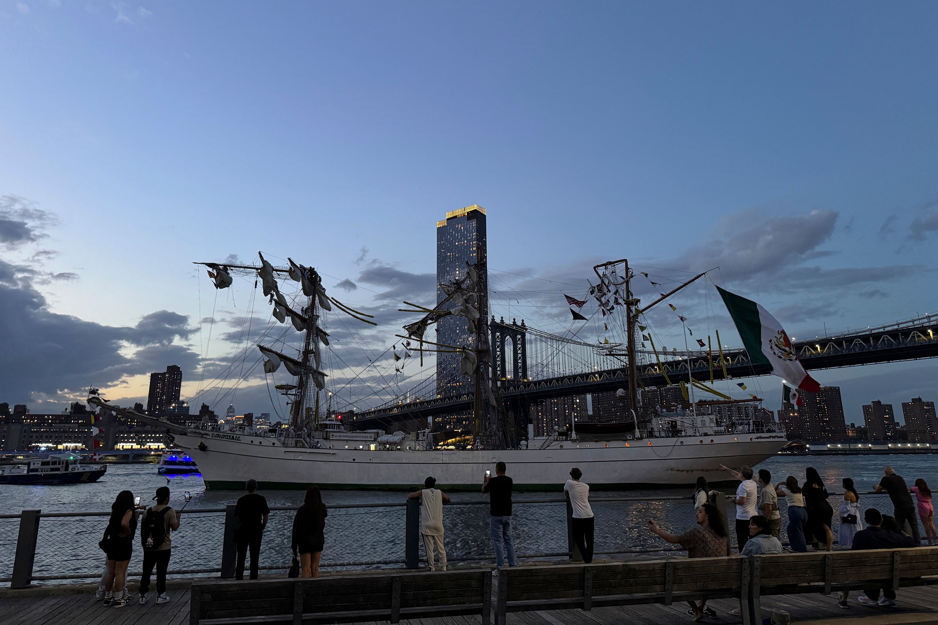 Pedestrians walking along Brooklyn Bridge Park look on as a masted Mexican Navy training ship sits stranded near the Manhattan Bridge after colliding with the Brooklyn Bridge