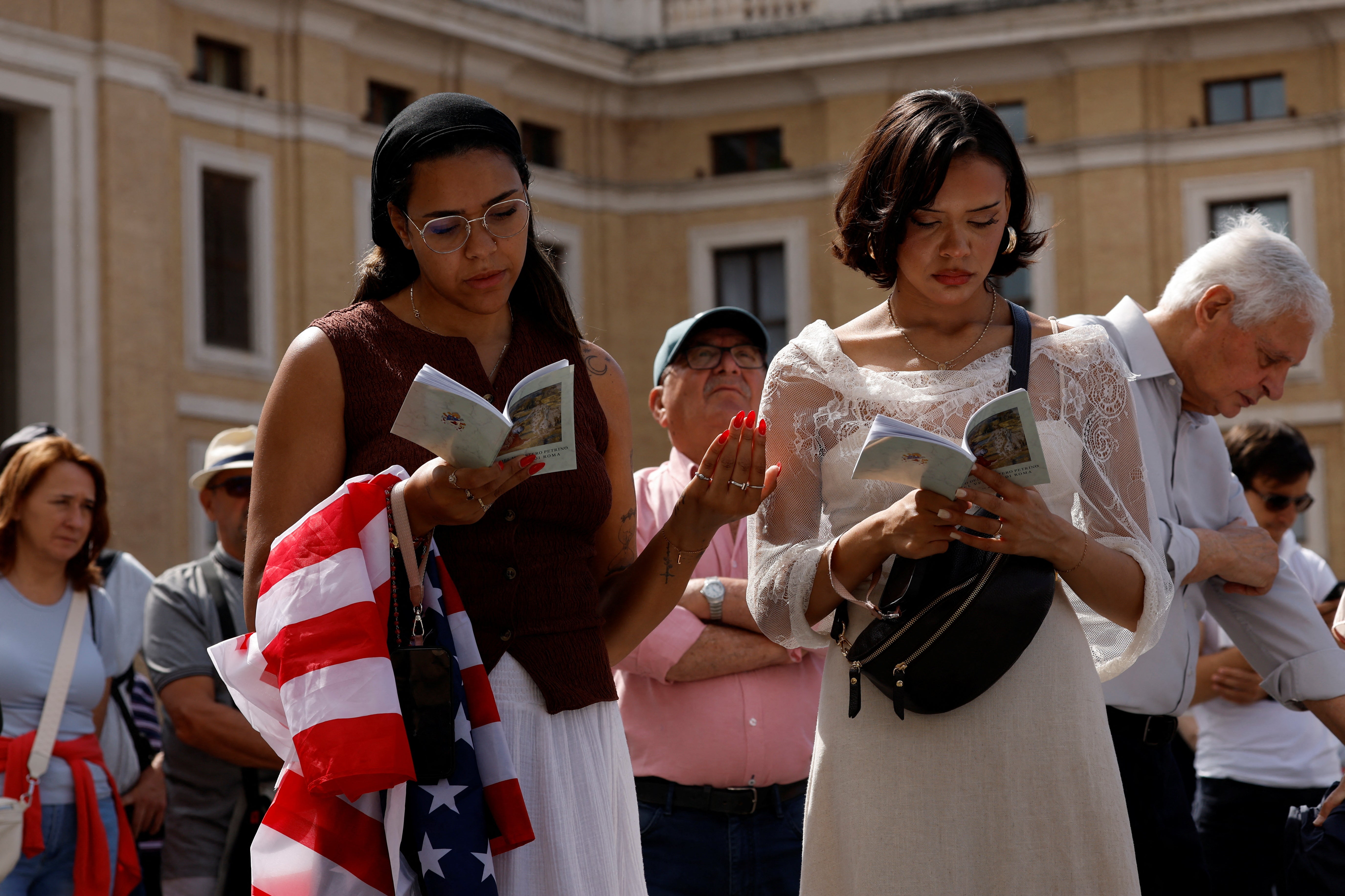 Women read books during Pope Leo XIV's inaugural Mass at the Vatican, in Rome, Italy