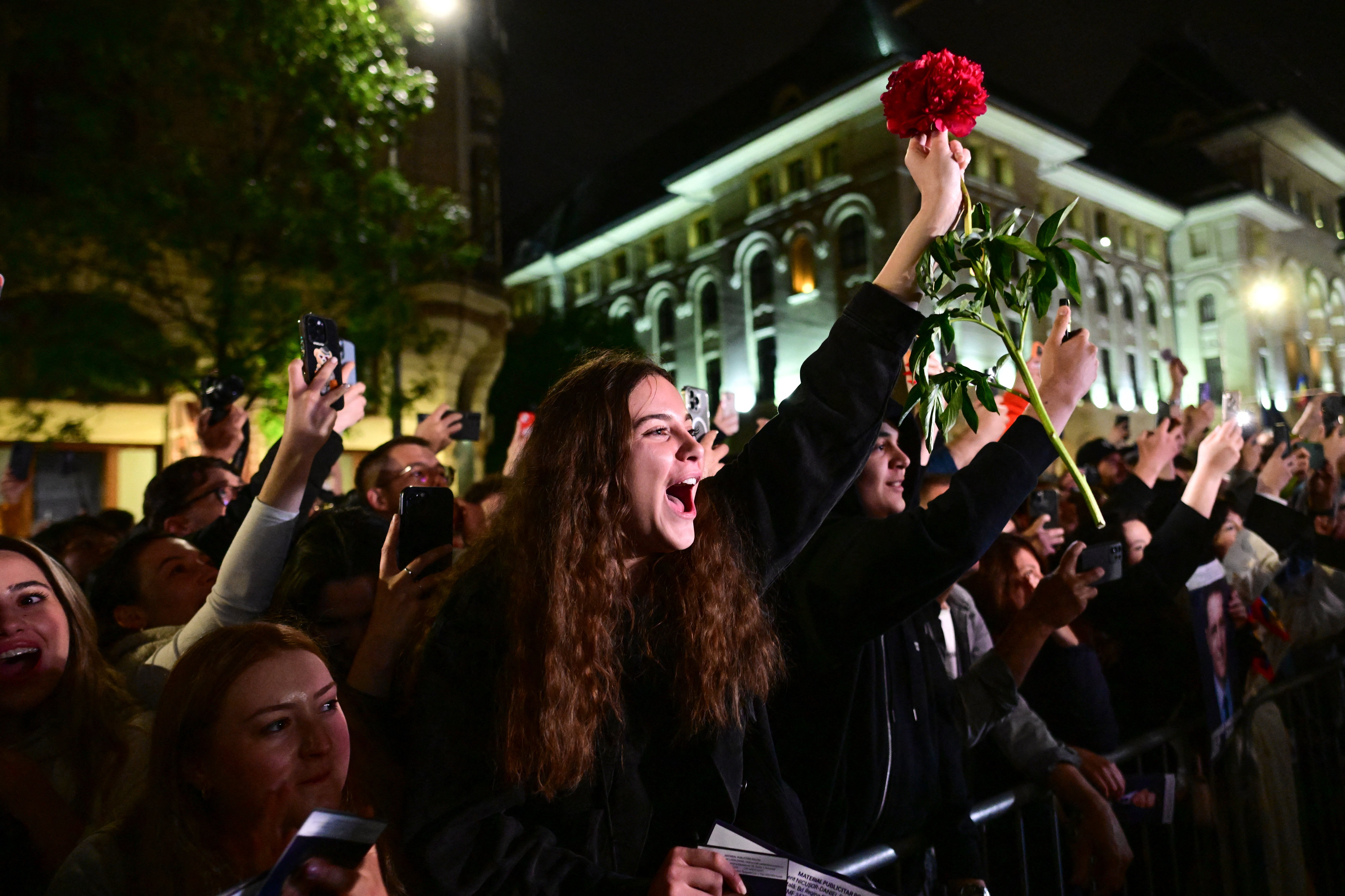 Supporters of Bucharest Mayor Nicusor Dan, who won a tense rerun of Romania's presidential election on Sunday - beating far-right nationalist George Simion who was more sympathetic to Moscow - cheer as he exit his campaign headquarters in Bucharest