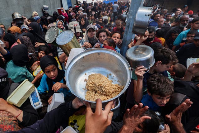 <p>Palestinians gather to receive a hot meal at a food distribution point in the Nuseirat camp for refugees in the central Gaza Strip </p>