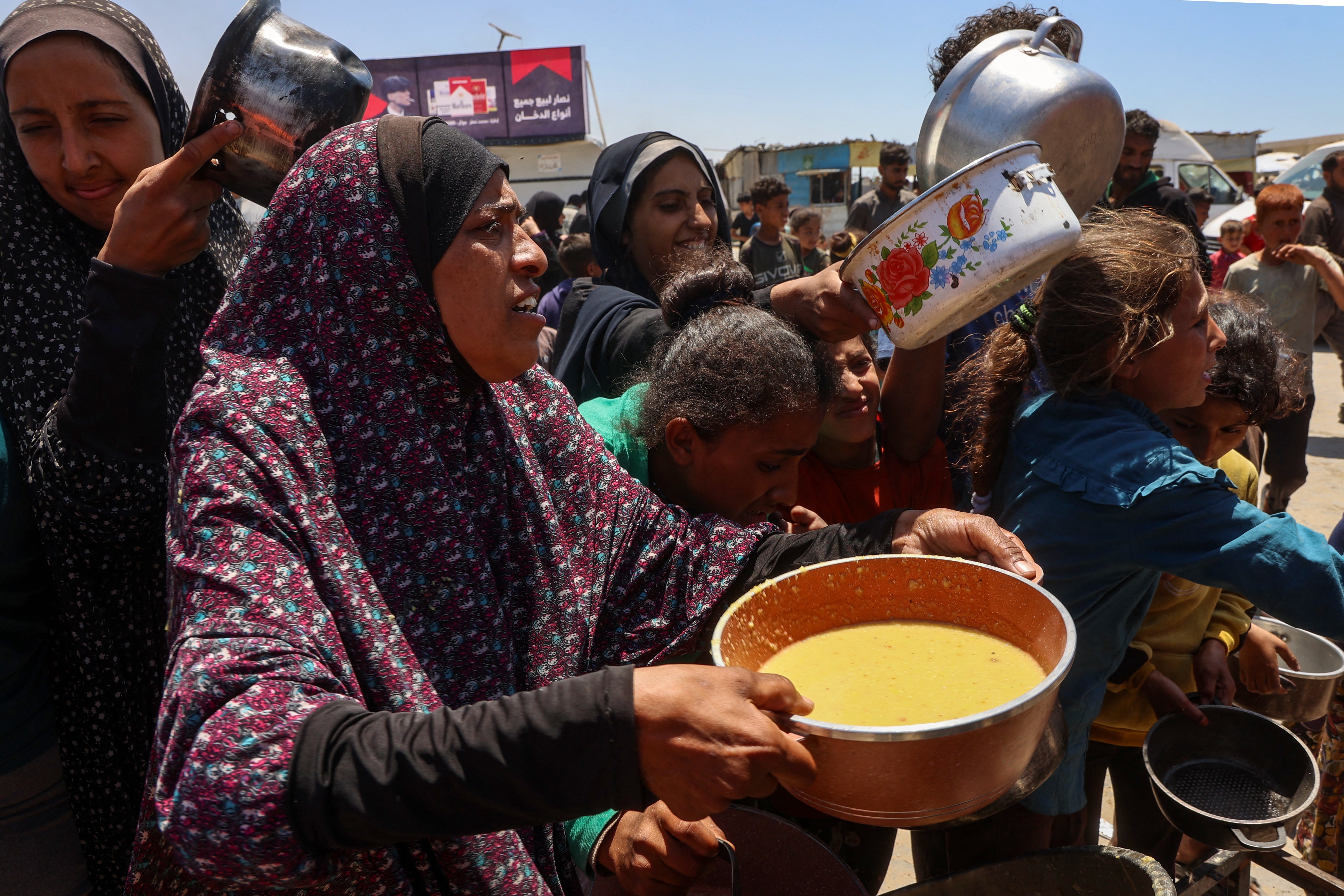 Palestinians line up to receive a hot meal at a food distribution point in the Al-Rimal neighbourhood in Gaza City on Wednesday