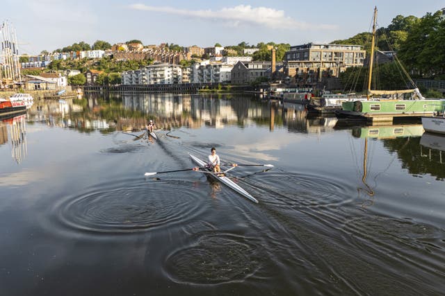 <p>Rowers break the glassy water surface along Bristol harbourside </p>