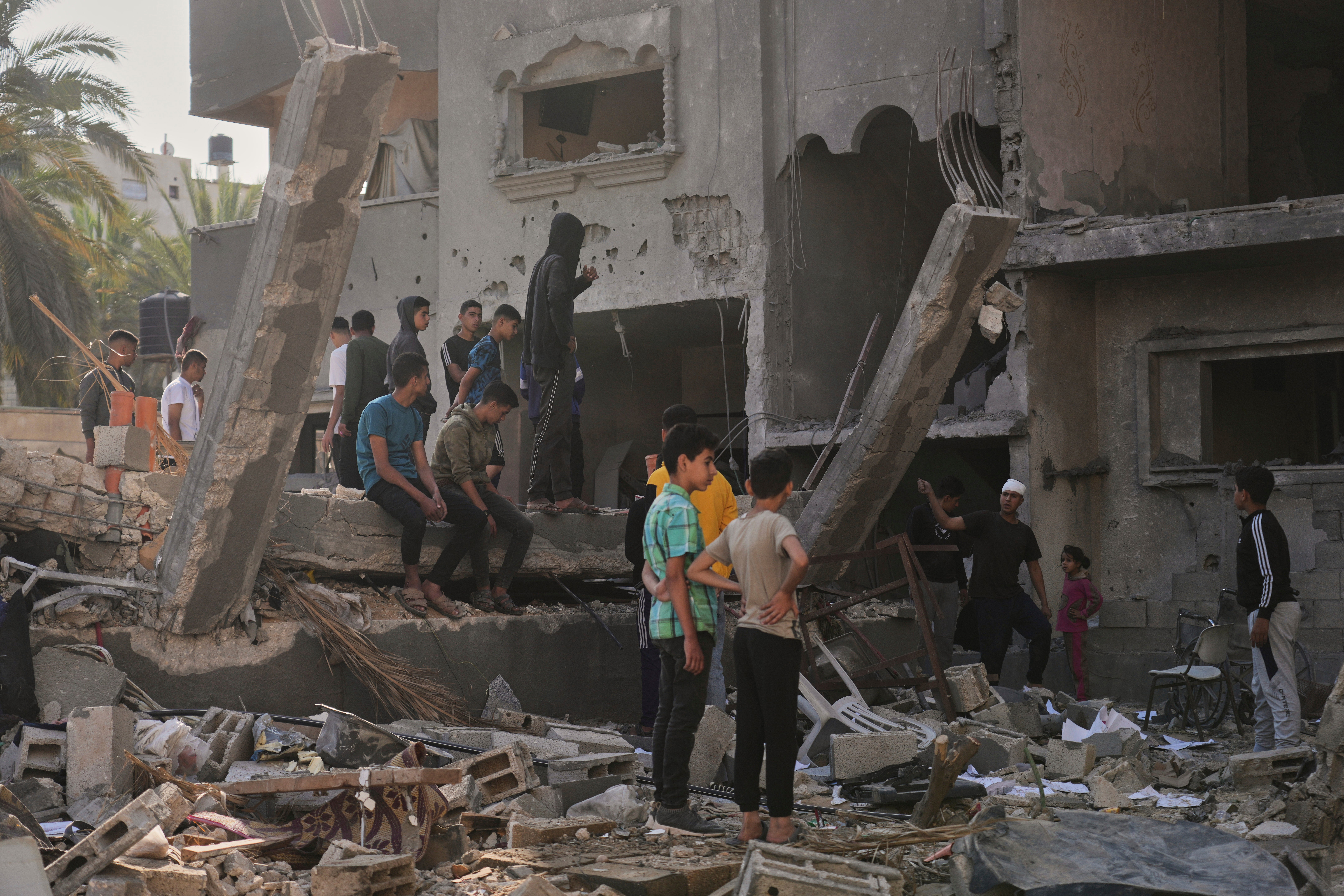 Palestinians inspect a house destroyed by an Israeli airstrikes in Deir al-Balah