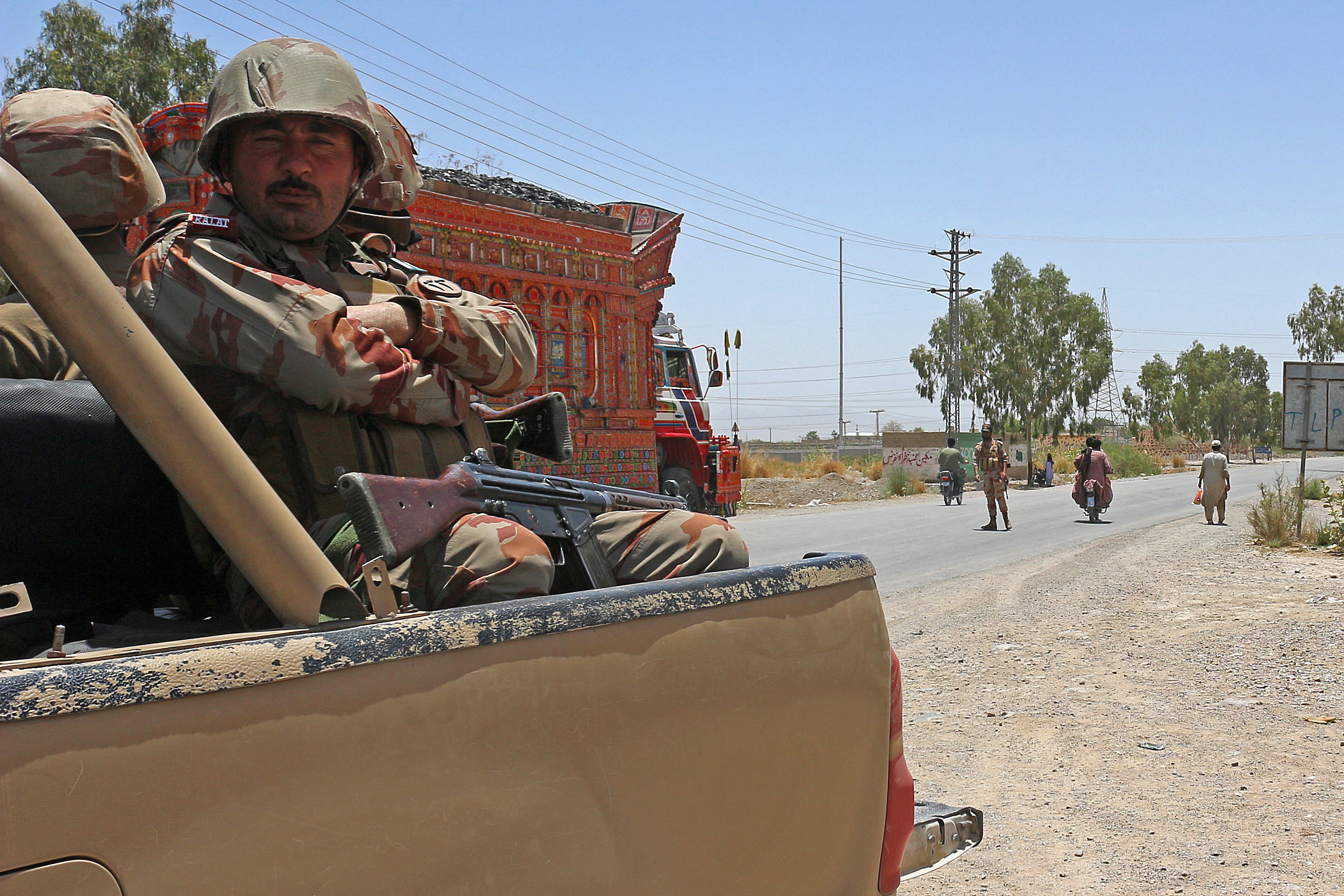 Security personnel guard along a street near the site of a school bus bombing in the Khuzdar district of Balochistan province