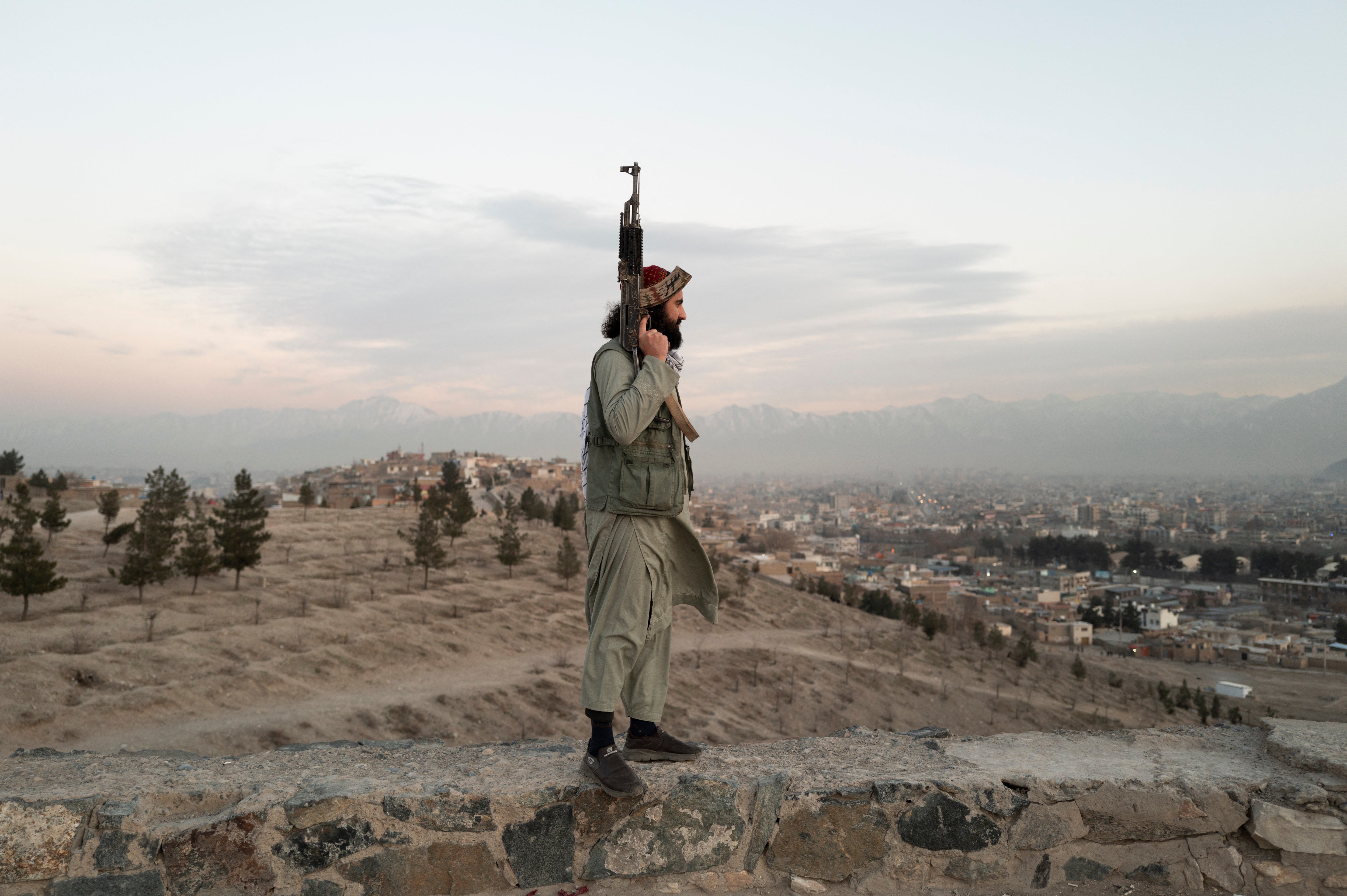 High above Kabul a Taliban armed with a Kalashnikov looks down on the city