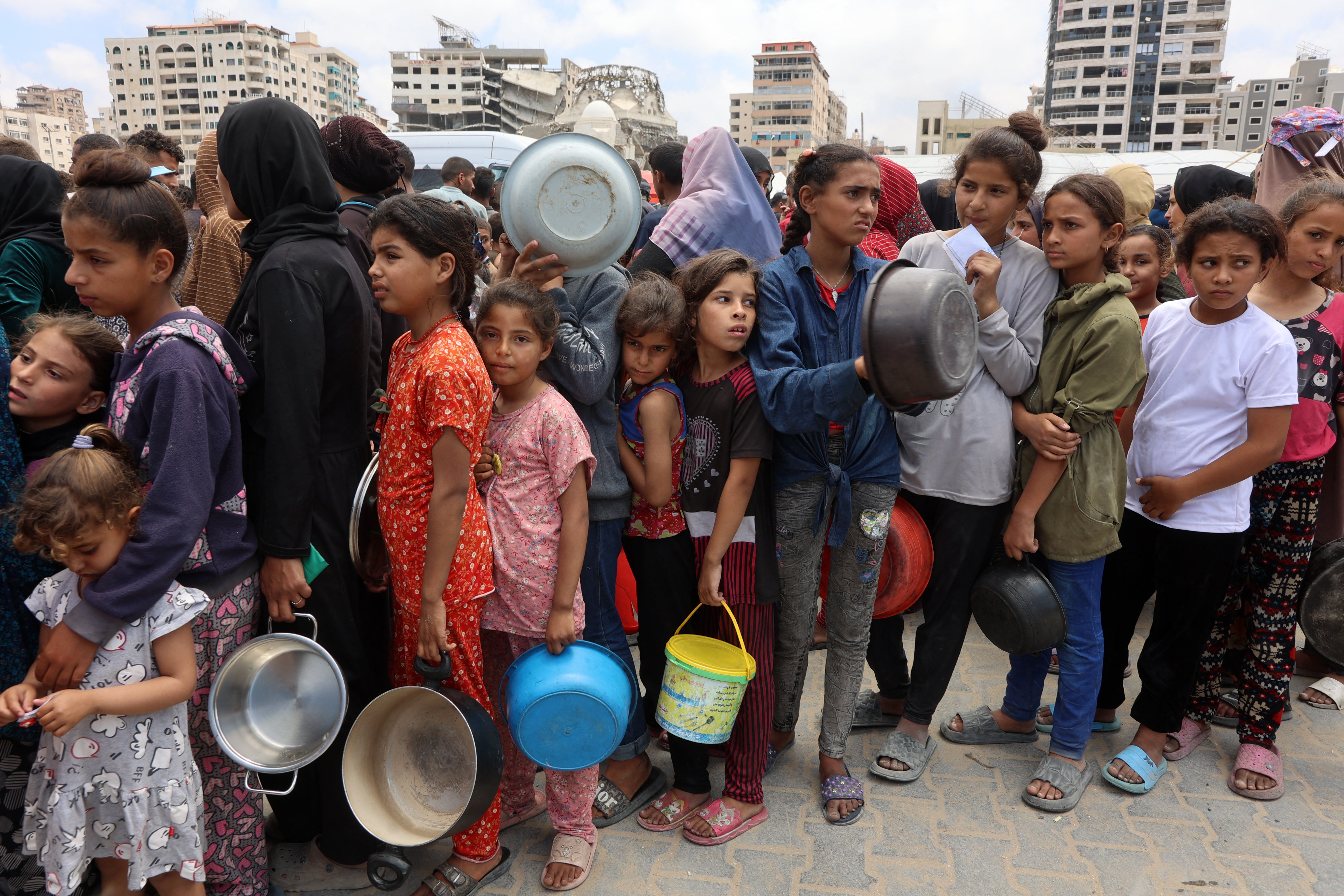 Palestinians, most of them children, queue in front of a hot meal distribution truck