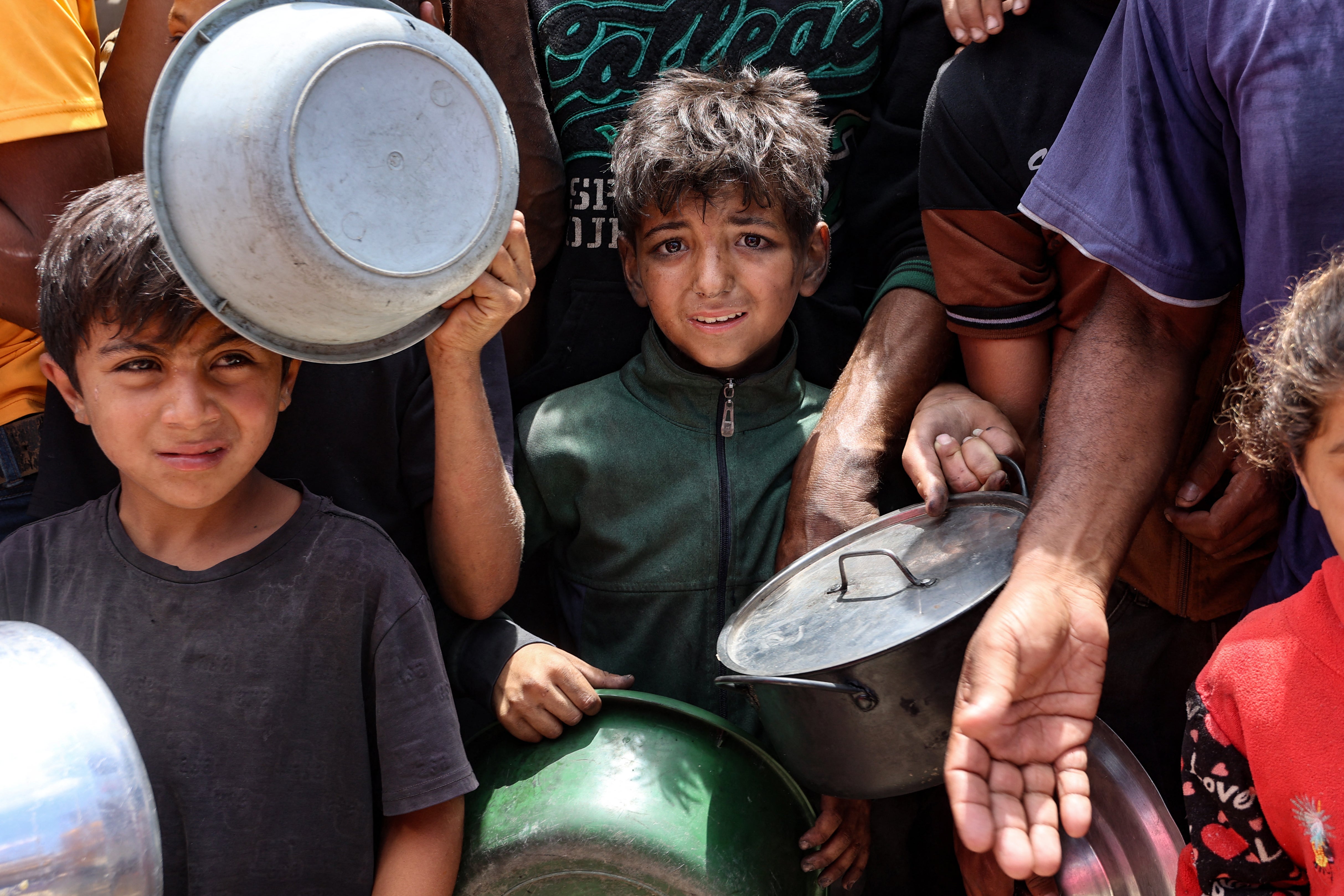 Palestinian children wait in front of a hot meal distribution truck