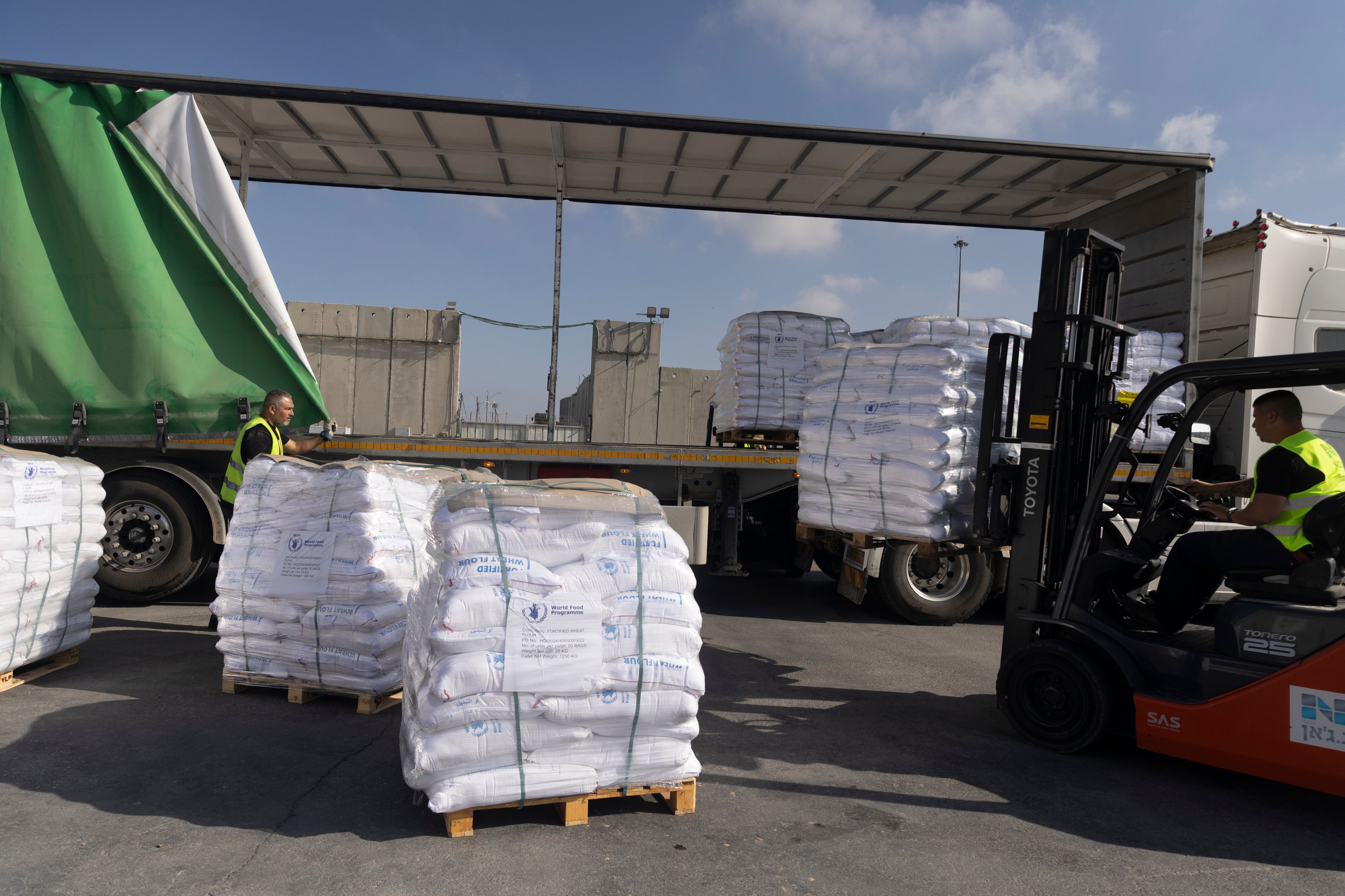 Workers unload a truck with humanitarian aid before entering the Gaza Strip at the Kerem Shalom Crossing