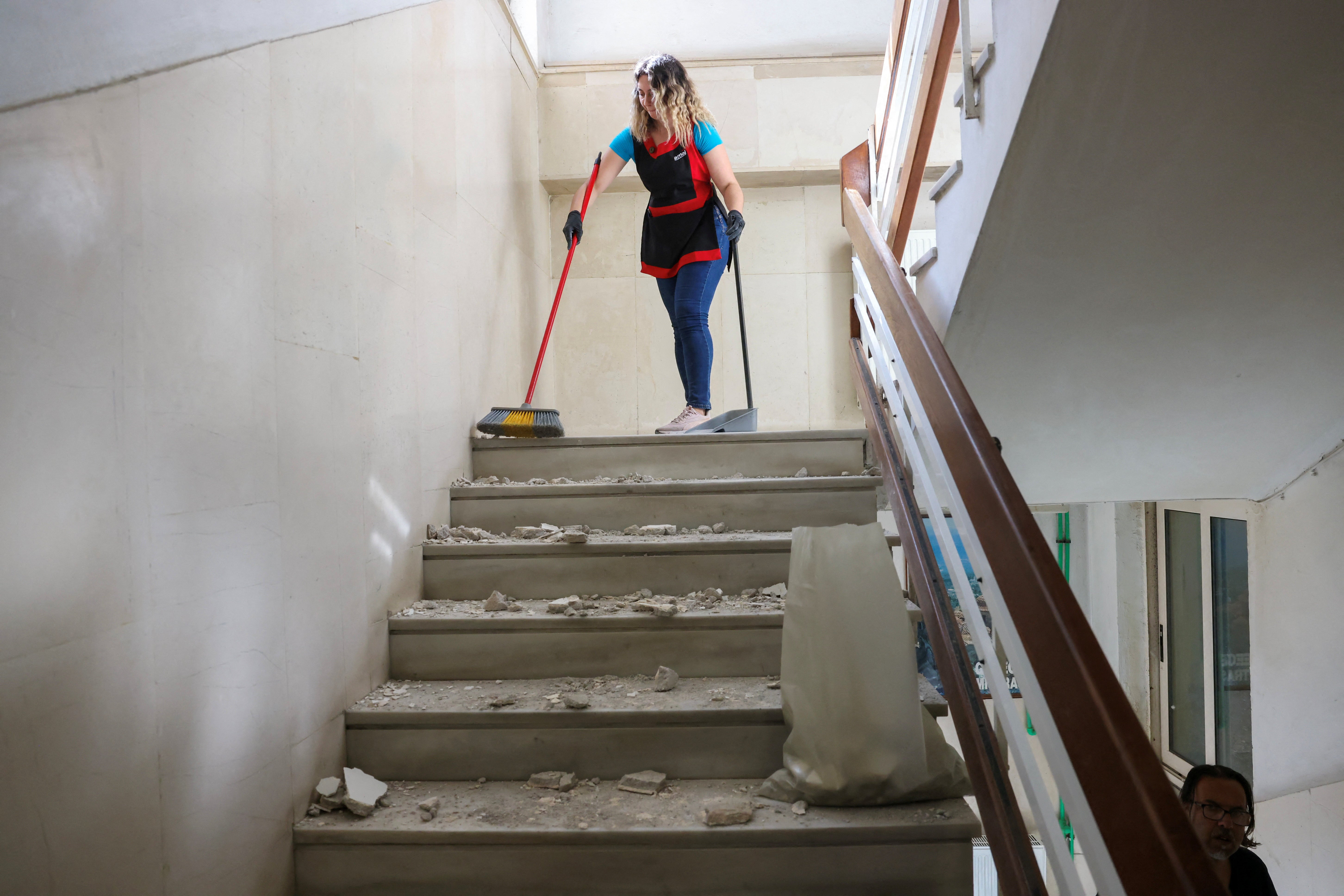A woman cleans debris from the stairs of a building, following an earthquake that hit the island of Crete, in Heraklion, Greece, 22 May 2025