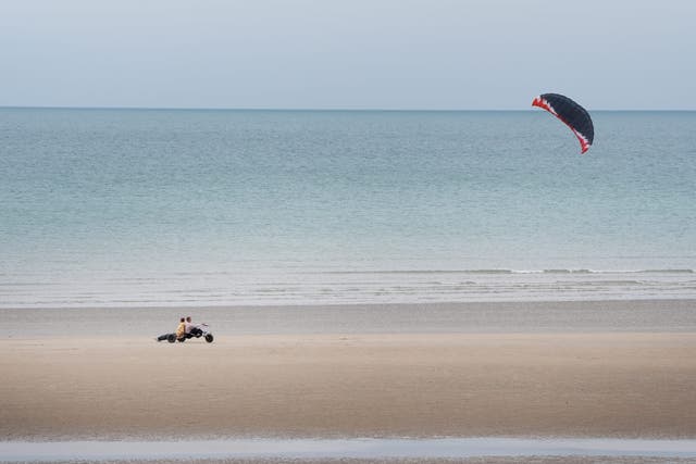 A kite buggy is raced along the beach during the cool windy conditions in Camber, East Sussex (Gareth Fuller/PA)