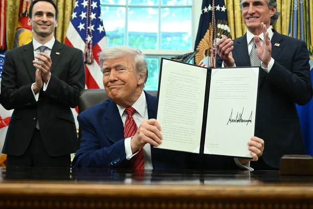 President Donald Trump at his desk holding an executive order with Interior Secretary Doug Burgum
