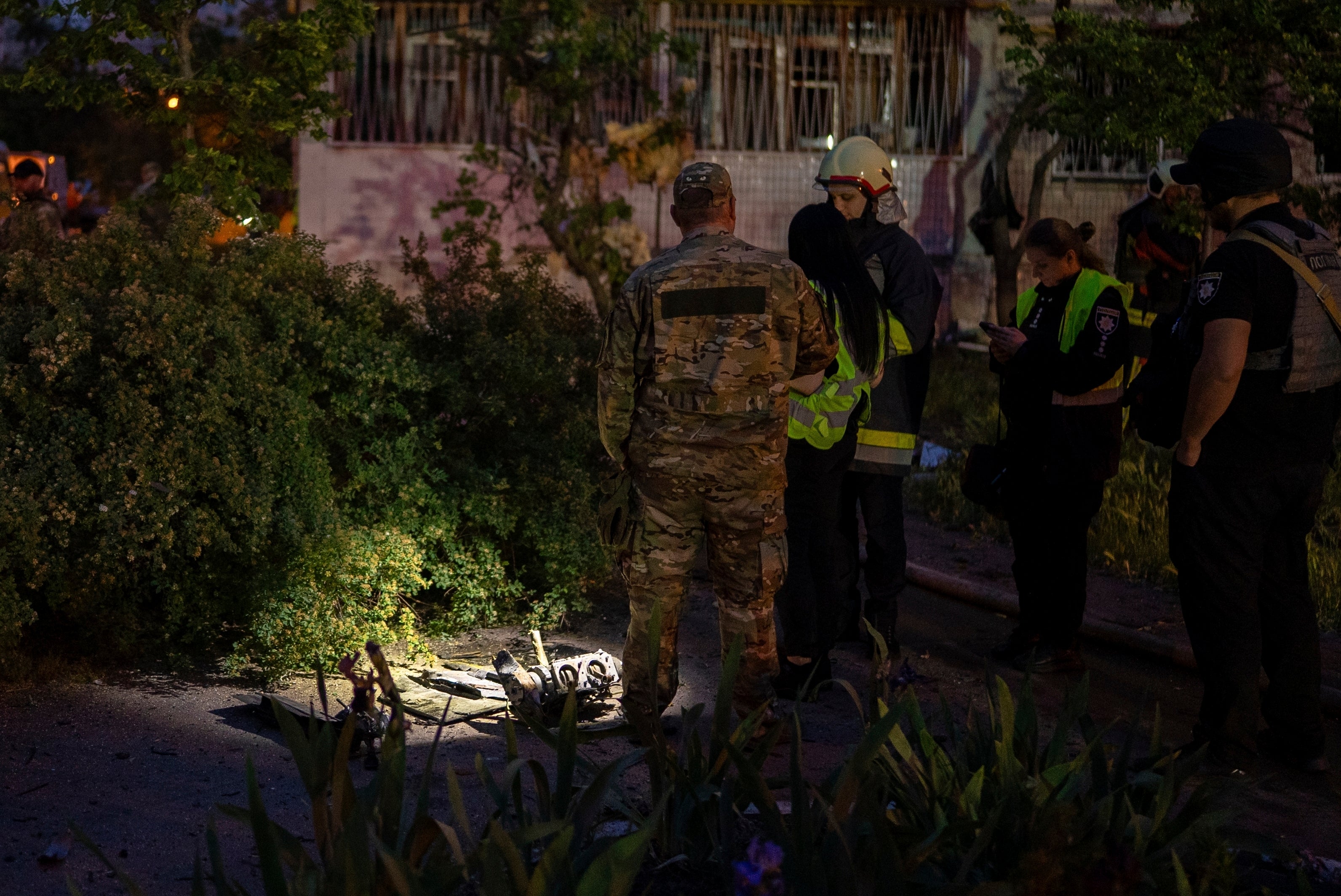 Police officers investigate fragments of a Russian drone at the site of a residential building damaged after a Russian attack in Kyiv