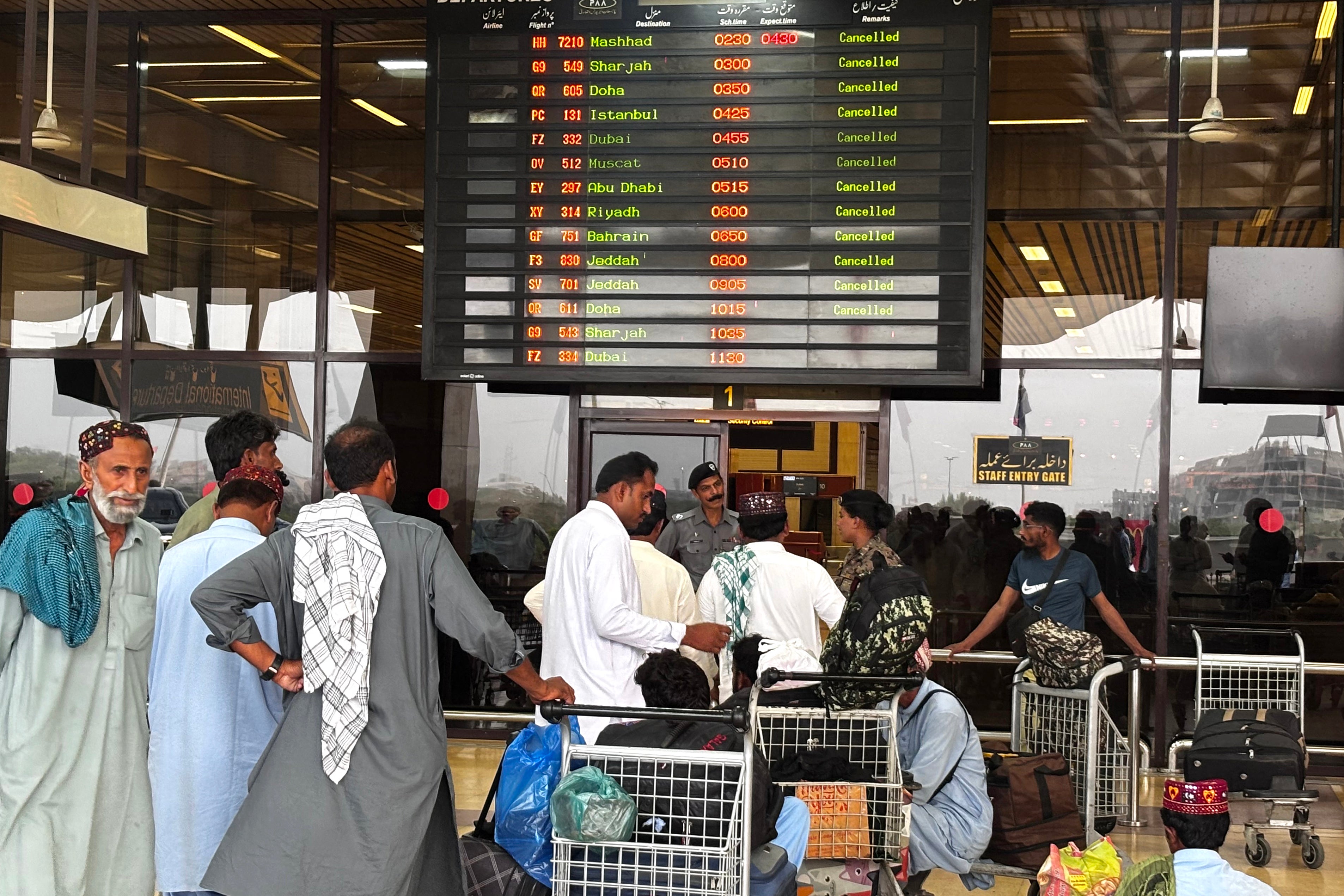 Passengers wait at Jinnah International Airport after all domestic and international flights were cancelled in Karachi