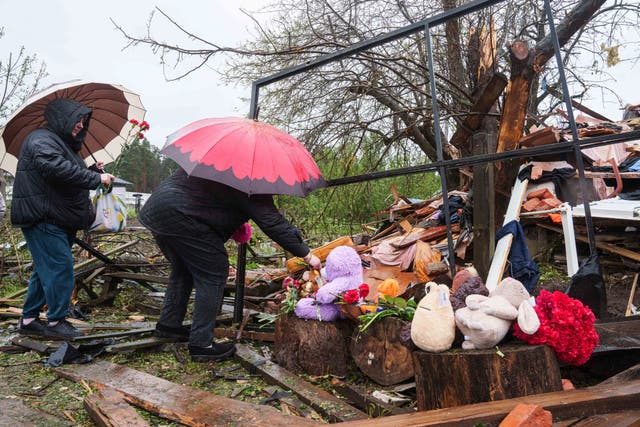 <p>Women lay flowers by the rubble of a destroyed house where three children were killed by a Russian strike in Korostyshiv, Zhytomyr region, on Sunday</p>