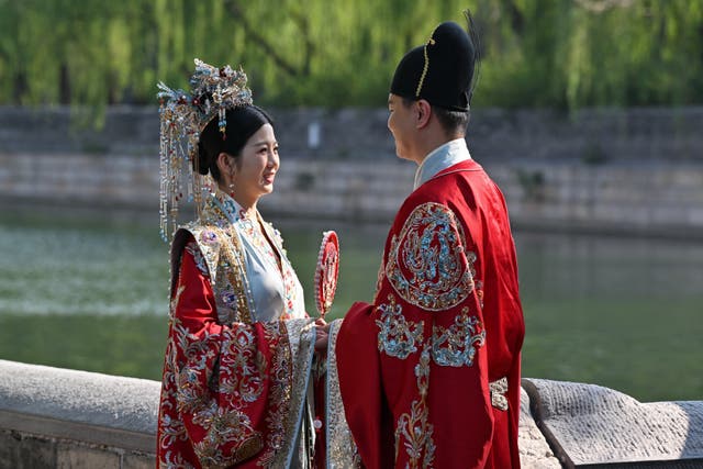 <p>A couple in traditional costumes pose for a wedding photo shoot at the Forbidden City in Beijing</p>