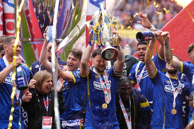 <p>AFC Wimbledon captain Jake Reeves lifts the trophy after the Sky Bet League Two play-off final at Wembley Stadium</p>