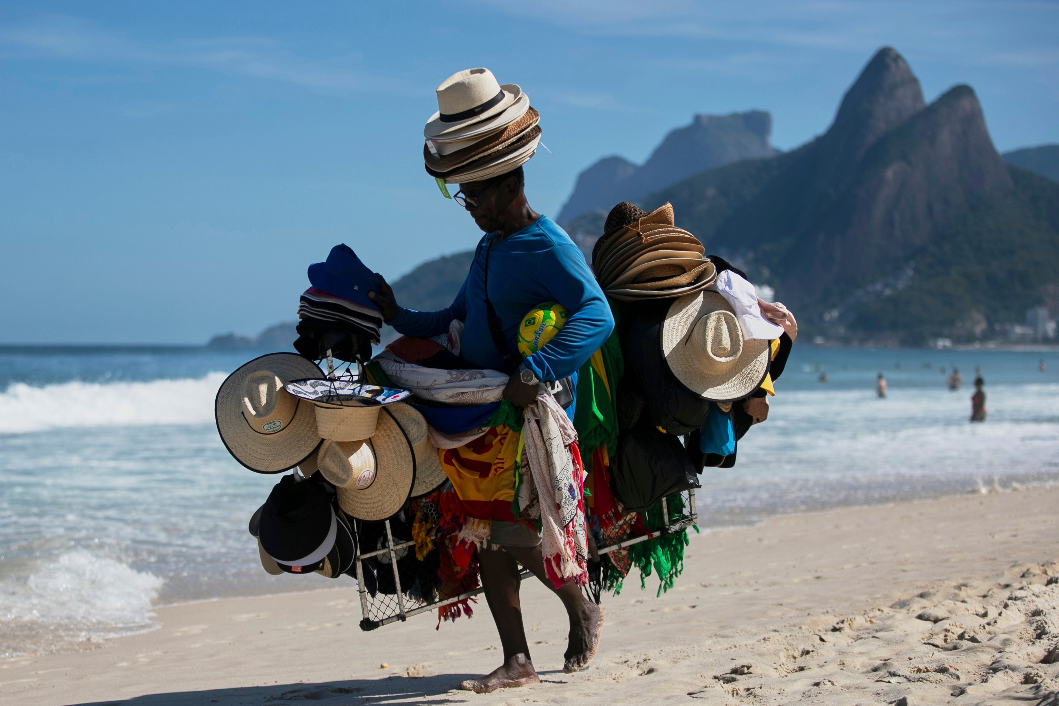 A vendor walks with his hats and beachwear along Ipanema Beach in Rio de Janeiro, Sunday, May 25, 2025. (AP Photo/Bruna Prado)