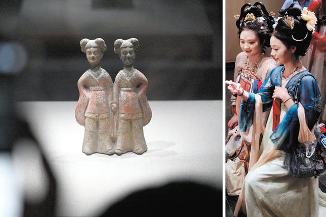 <p>Visitors in traditional Chinese attire admire the hand-holding pottery figurine at the Luoyang Museum</p>