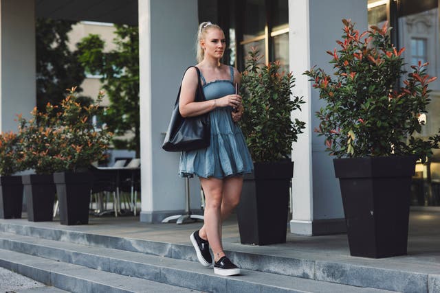 <p>A woman wearing a summer dress and trainers.</p>