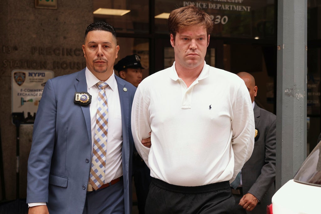 William Duplessie, right, is escorted out of the New York Police 13th Precinct after turning himself in on charges of kidnapping and false imprisonment, Tuesday, May 27, 2025, in New York