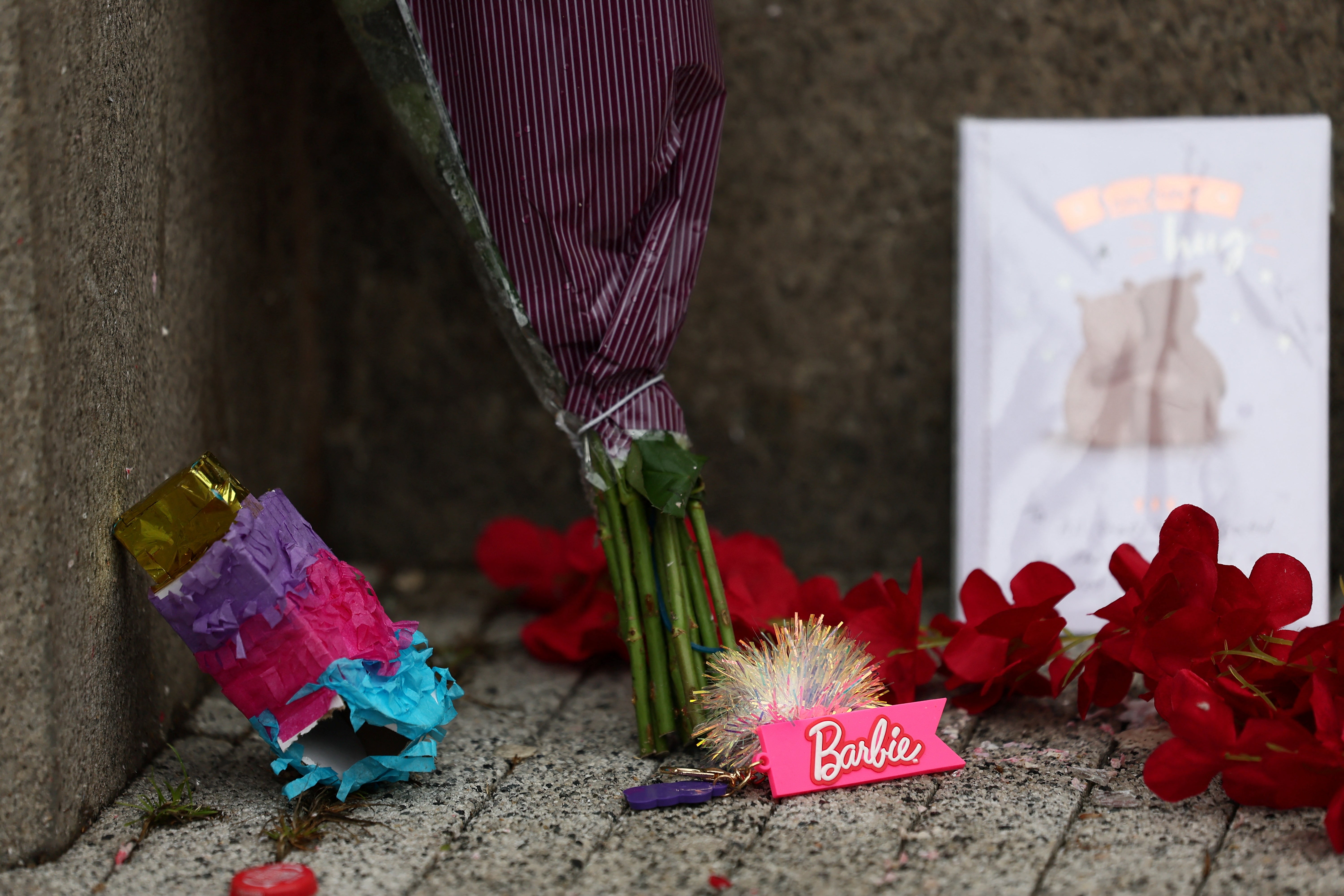 A Barbie keychain, flowers and cards lie on the ground near the site of an incident where a car plowed into a crowd of Liverpool fans