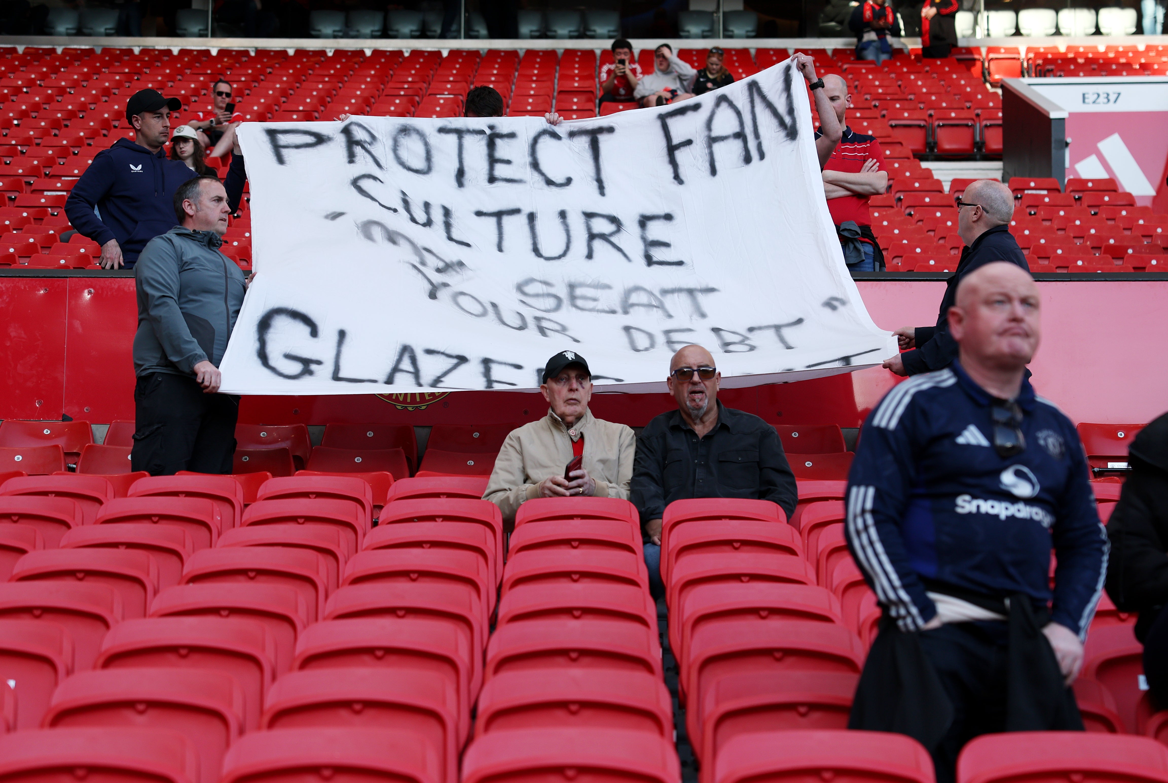 Fans of Manchester United display a banner which reads "Protest fan culture 'my seat your debt', Glazers out"