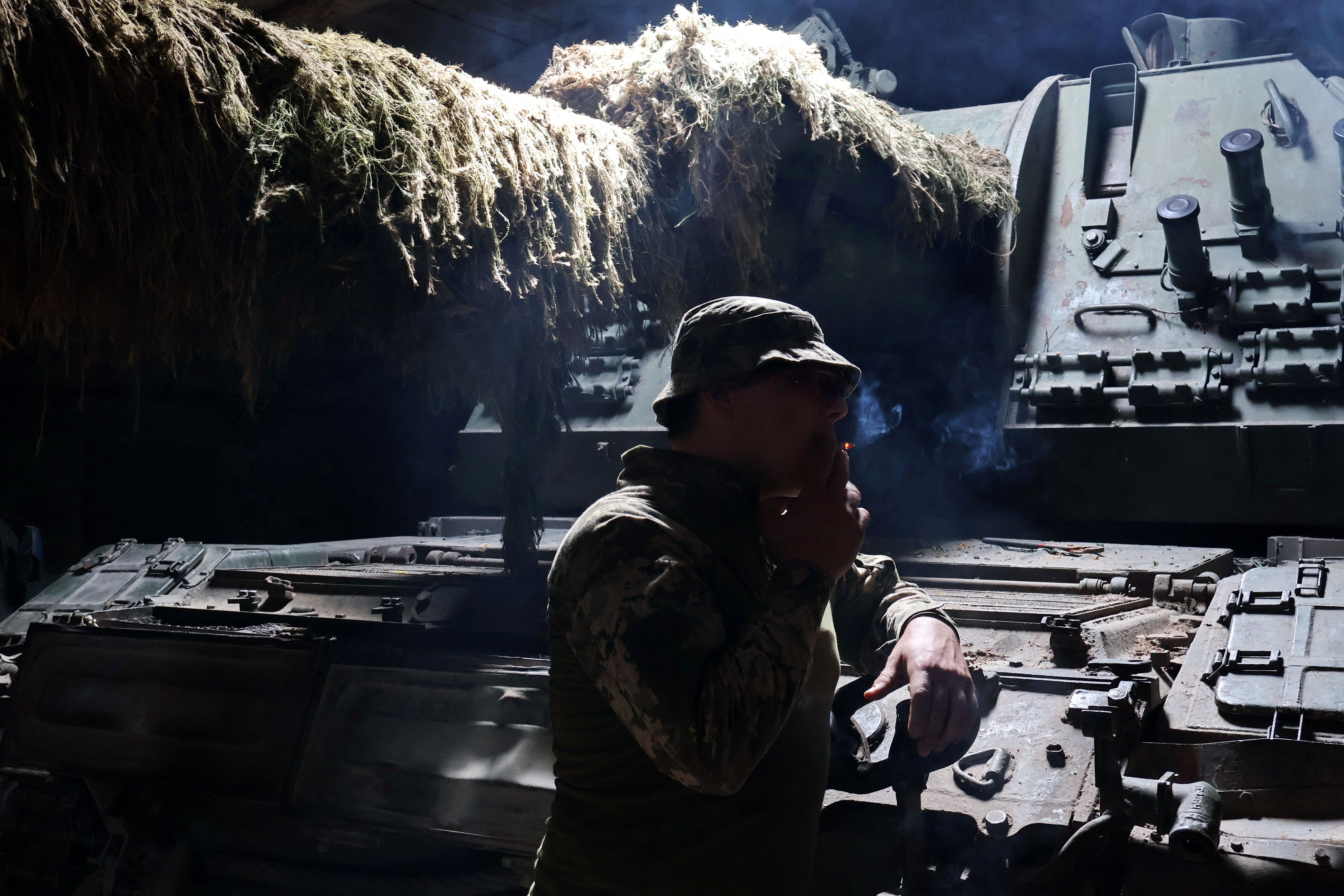 A Ukrainian serviceman of the 65th Separate Mechanized Brigade of the Ukrainian Armed Forces smokes next to a captured Russian 2S19 Msta-S self-propelled howitzer before going to a position near a front line in Zaporizhzhia region, Ukraine
