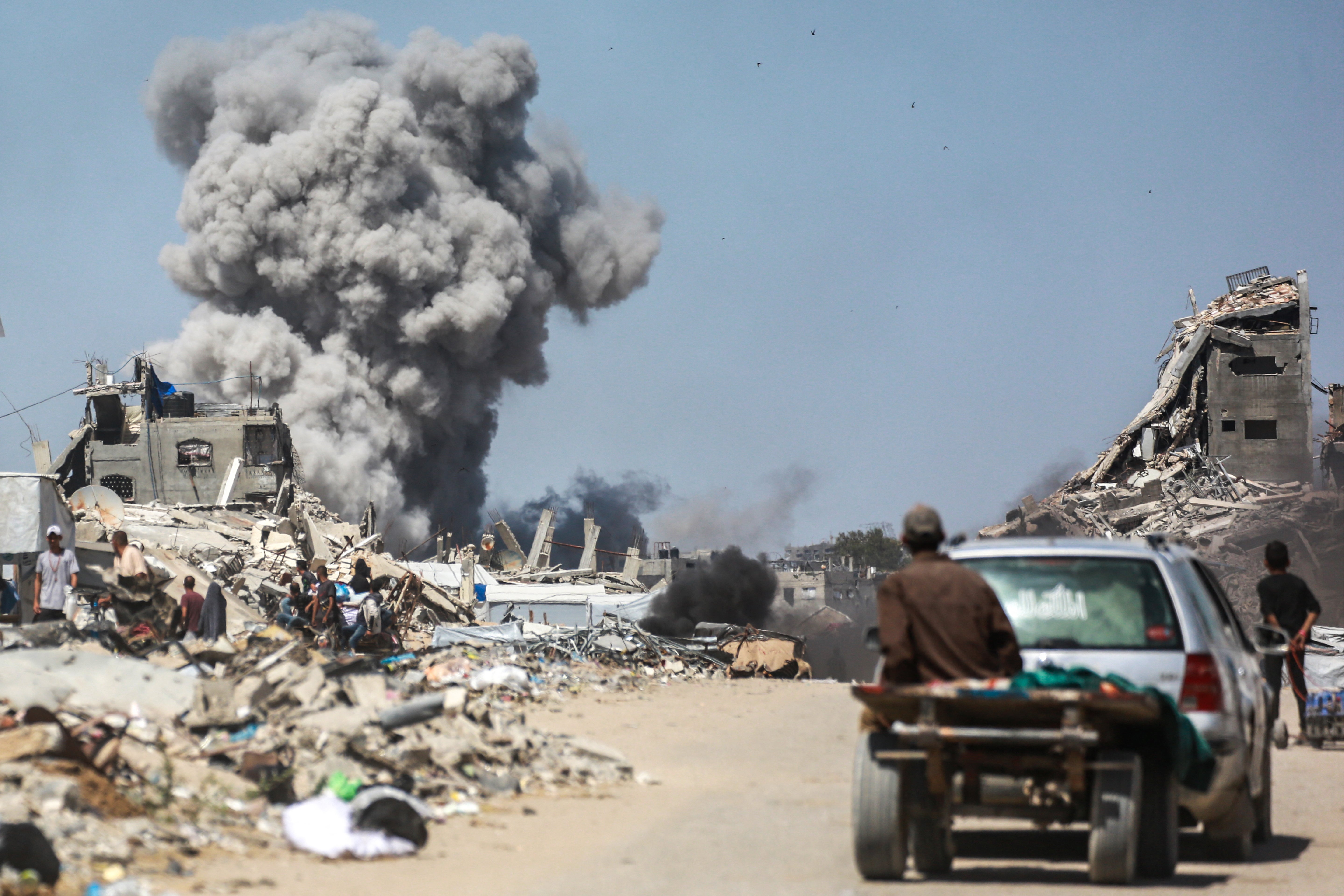 People watch as smoke billows following an Israeli strike in Jabalia, in the northern Gaza Strip on 25 May 2025
