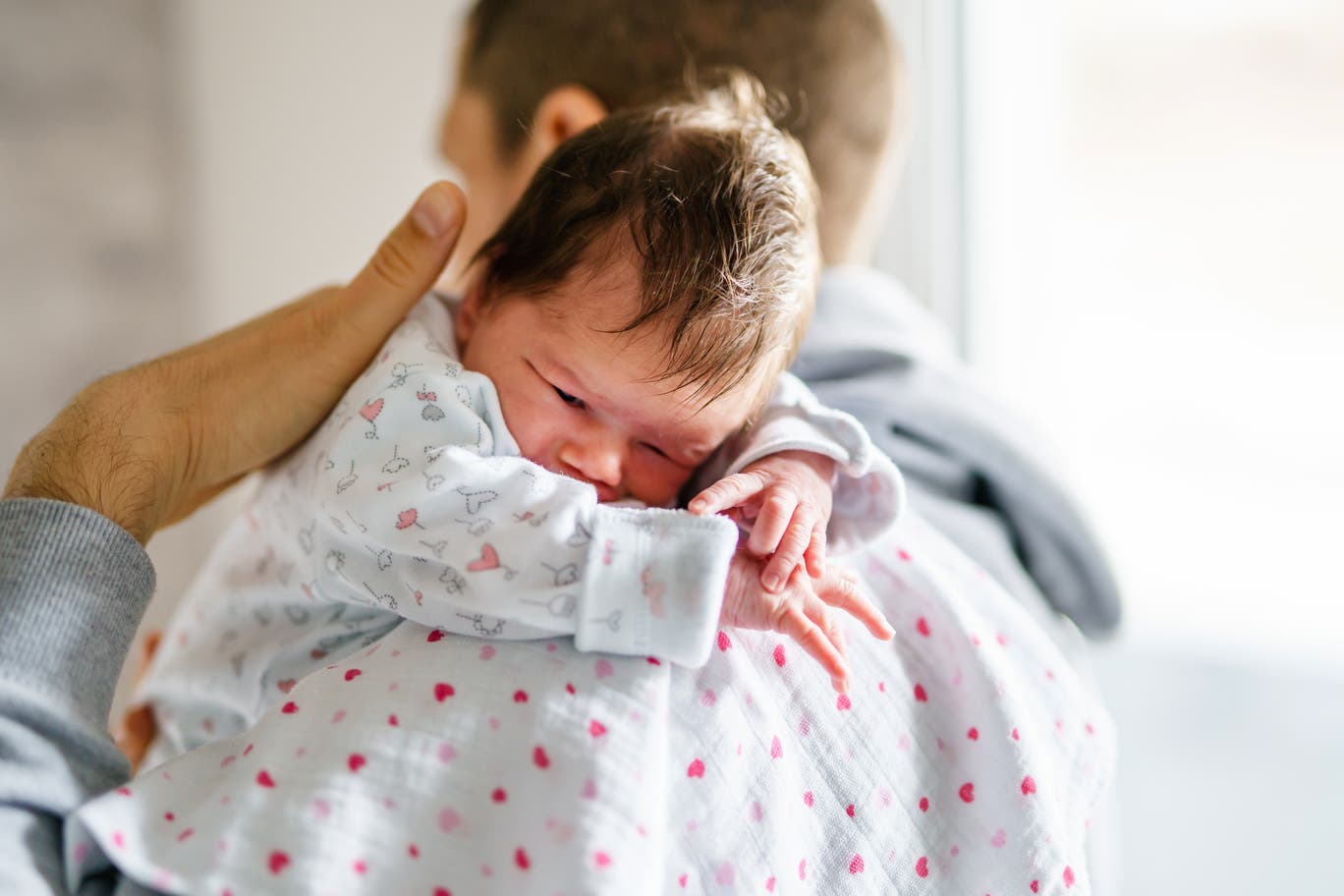 An infant is seen resting on a father's shoulder