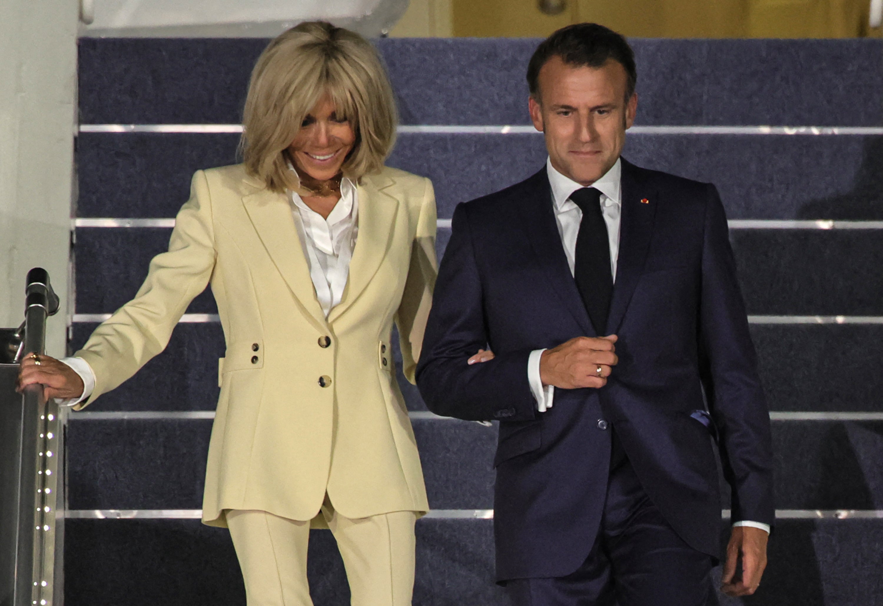 Emmanuel and Brigitte Macron were pictured smiling arm-in-arm as they walked down the steps of France's presidential plane in Indonesia