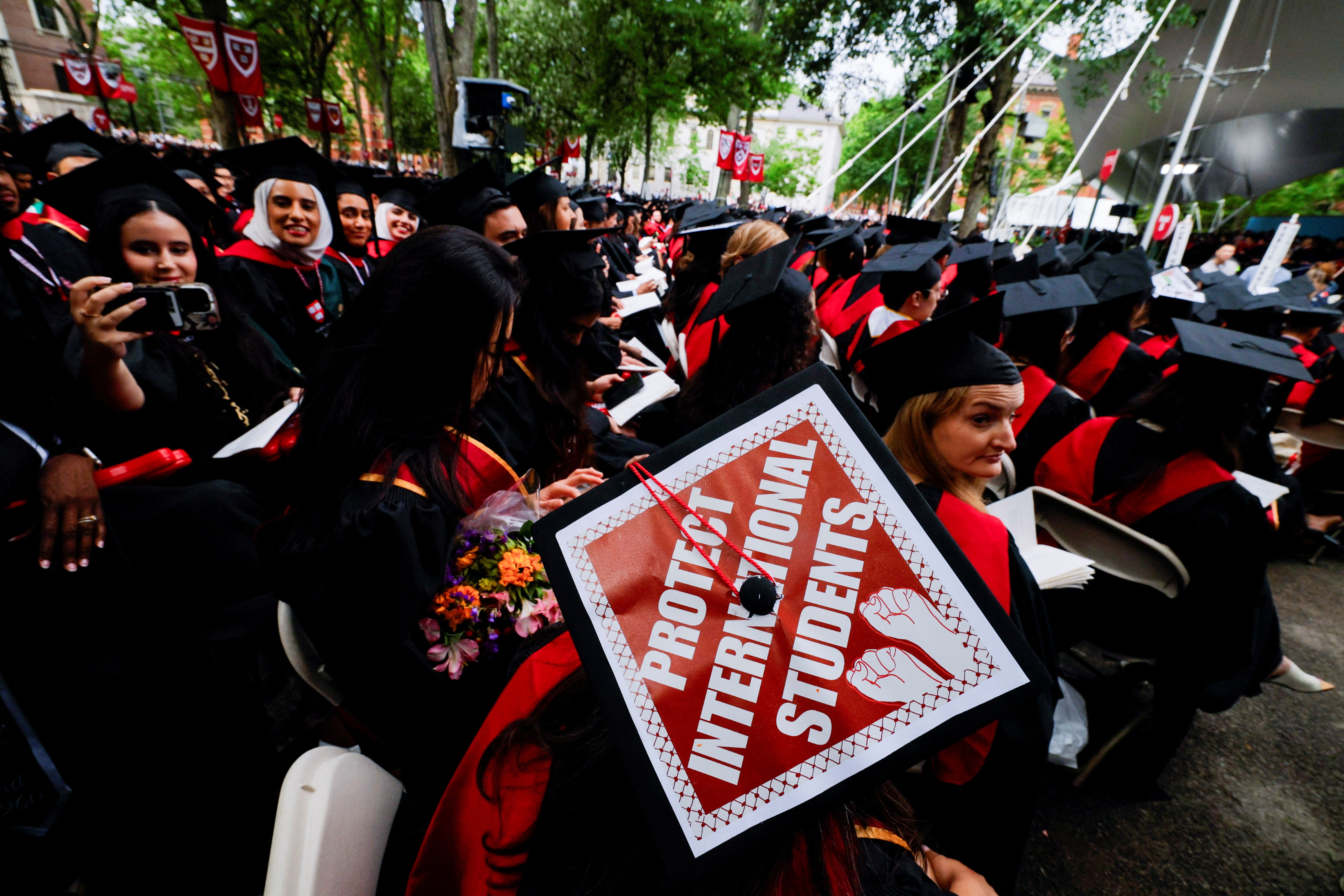 A student of graduates is wearing their hat who, with support for international students during the opening ceremonies of Harvard University on May 29, blocked the Trump administration from the termination of foreign student registrations