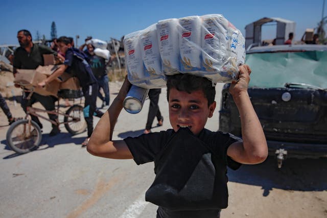 <p>A Palestinian boy carries US aid back to his family at Gaza’s Netzarim Corridor</p>