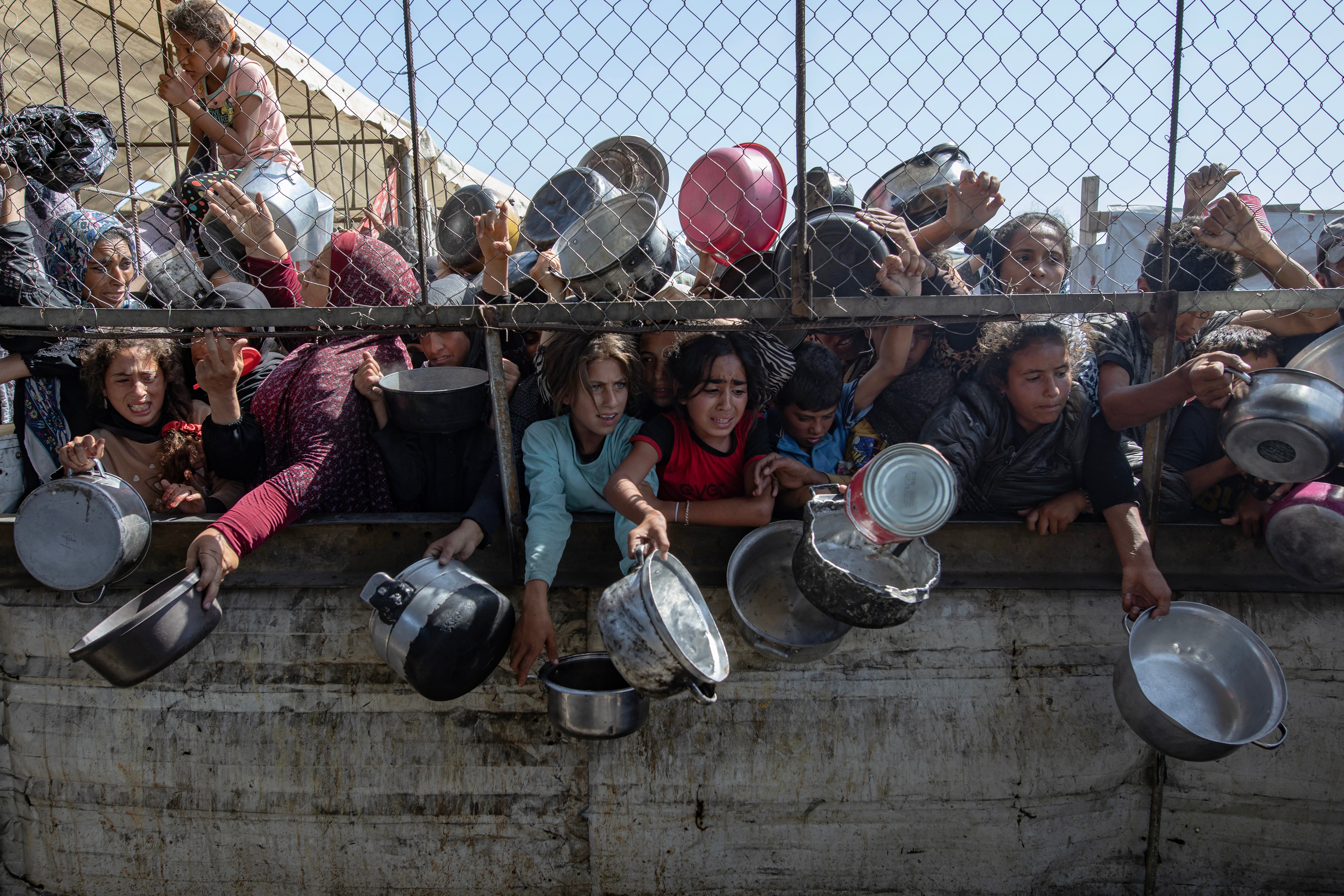 Internally displaced Palestinians gather outside a charity kitchen to receive limited rations amid a shortage of food, in Khan Younis, southern Gaza Strip