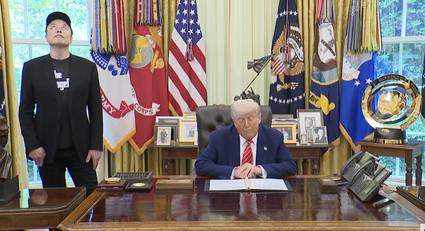 Elon Musk seems distracted as he stands alongside President Donald Trump in the Oval Office on his last official day as a special government employee.
