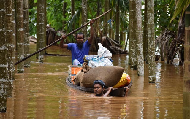 <p>People carry their belongings through floodwaters in Nagaon, Assam, on 31 May 2025</p>