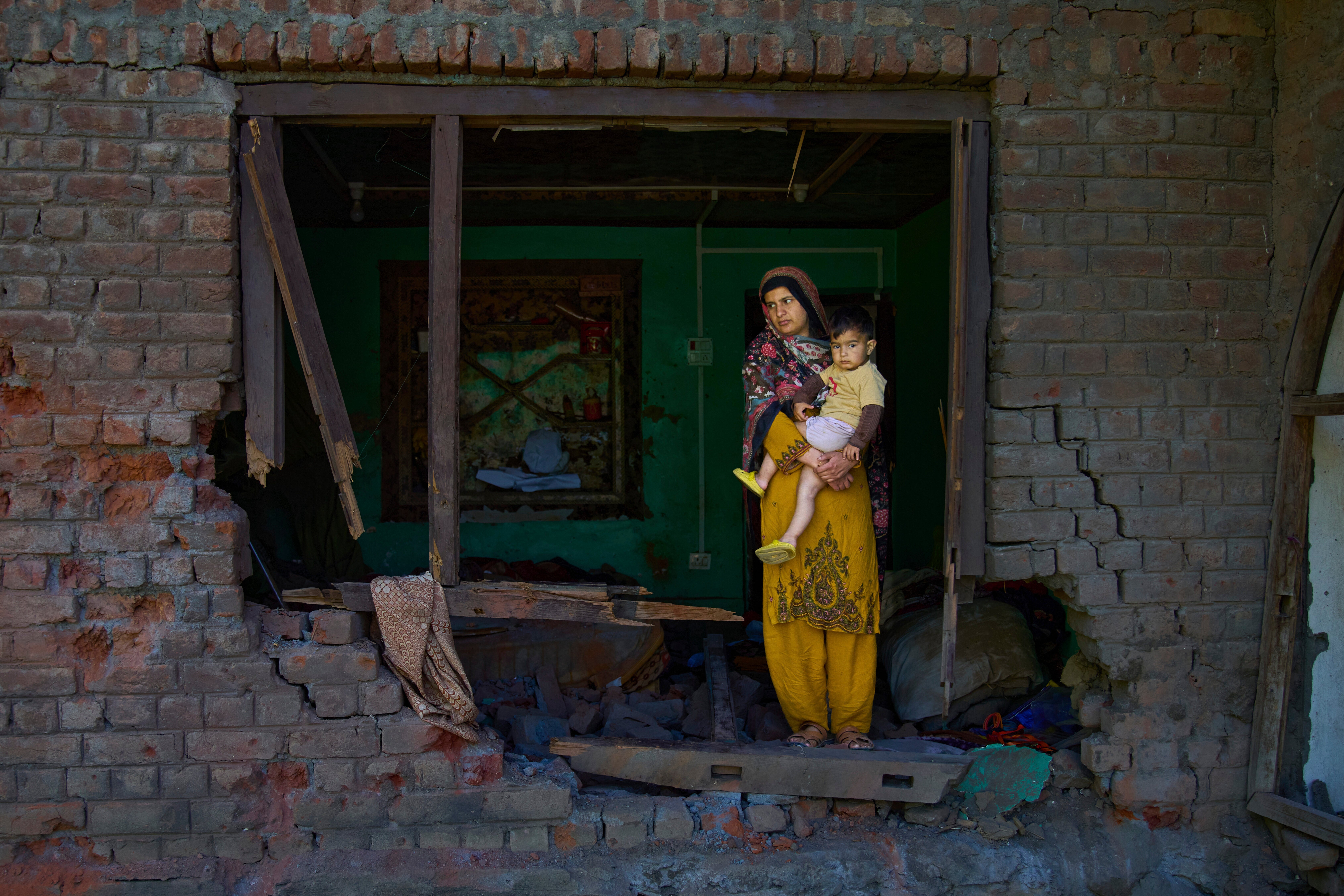 A woman holds her child in their house Gingal, Kashmir, which was damaged in shelling by Pakistan