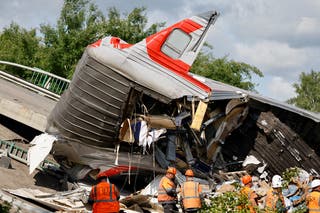Dossier: Les services d'urgence se rassemblent près du chariot détruit sur les lieux après qu'un pont routier s'effondre sur une voie ferrée après avoir déraillé un train approchant dans la zone de brination