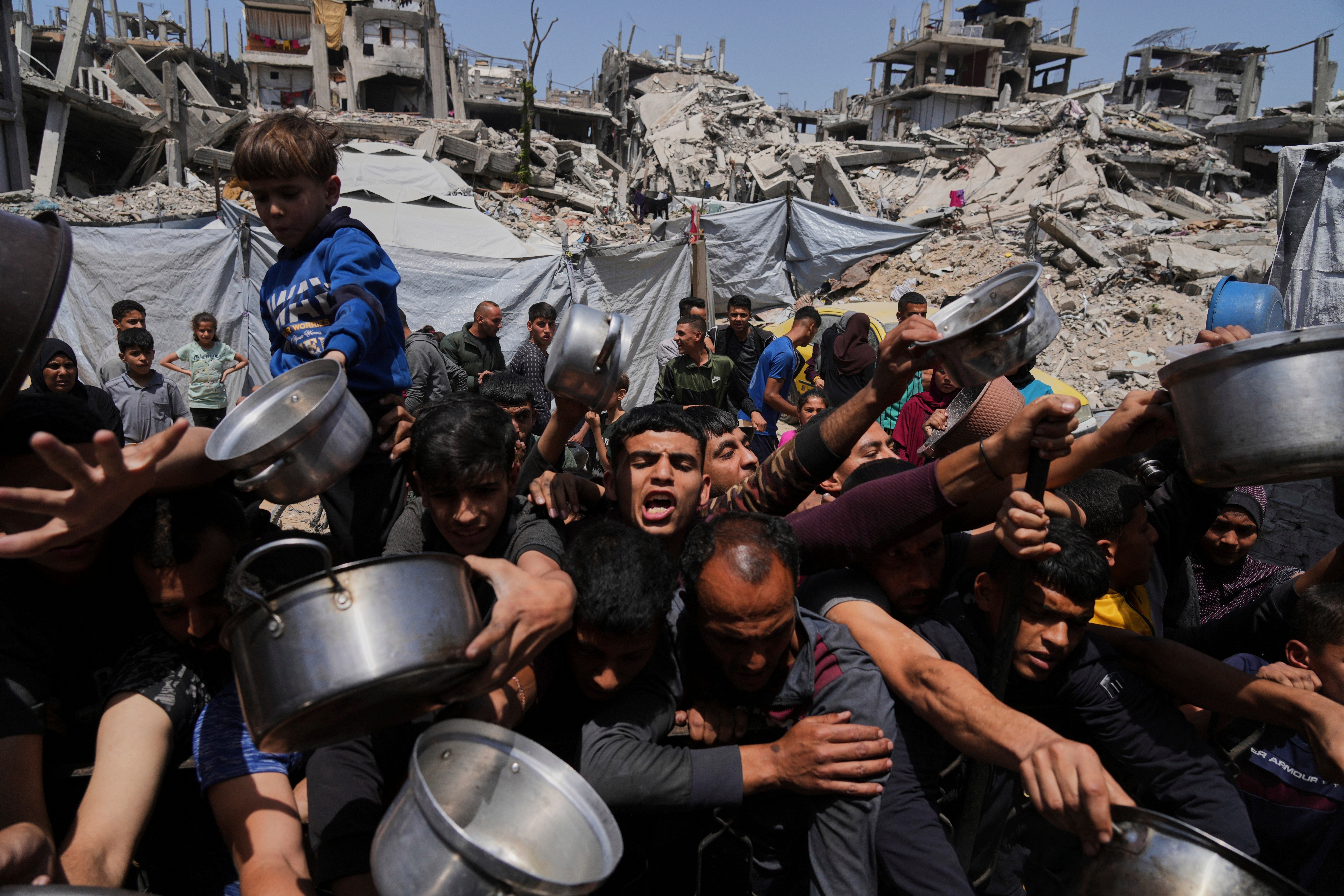 Palestinians struggle to bring donated food in the kitchen in the community in Beita Lahi, North Gaza Strip
