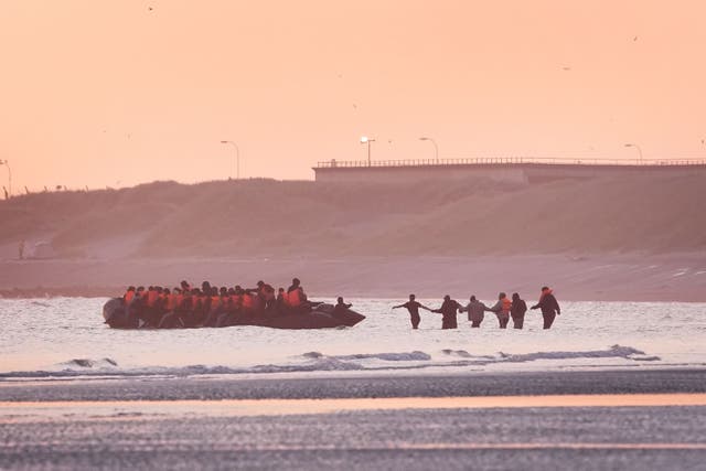 A group of people thought to be migrants wade into the sea to board an approaching small boat at Gravelines, France (Gareth Fuller/PA)