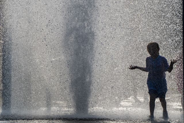 <p>A child plays in a burst water main in Liverpool (PA)</p>