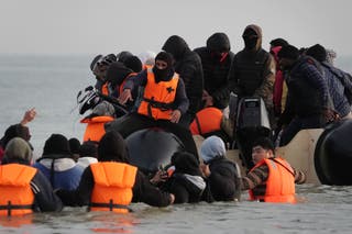 People thought to be migrants wade through the sea to board a small boat leaving the beach at Gravelines, France, in an attempt to reach the UK by crossing the English Channel (Gareth Fuller/PA)