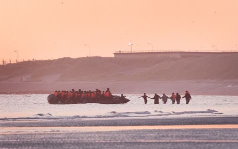 <p>A group of people thought to be migrants wade into the water to board an approaching small boat at Gravelines, France, in an attempt to reach the UK</p>