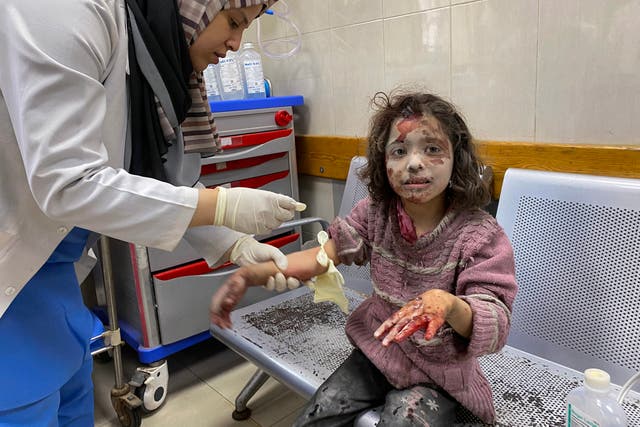 <p>A Palestinian medic cares for a girl who was injured in Israeli strikes on displacement tents in Khan Yunis in June</p>
